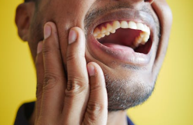 Man holding his jaw while suffering from severe tooth pain