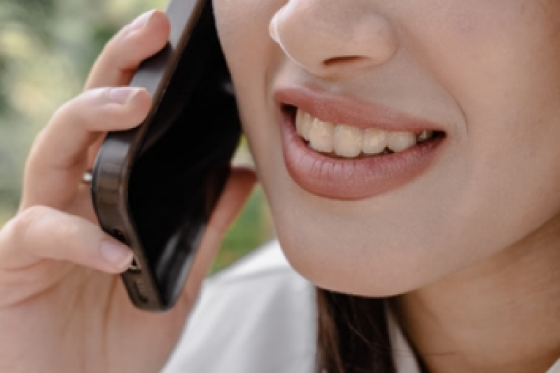 Woman talking on her phone with visibly stained and damaged teeth.
