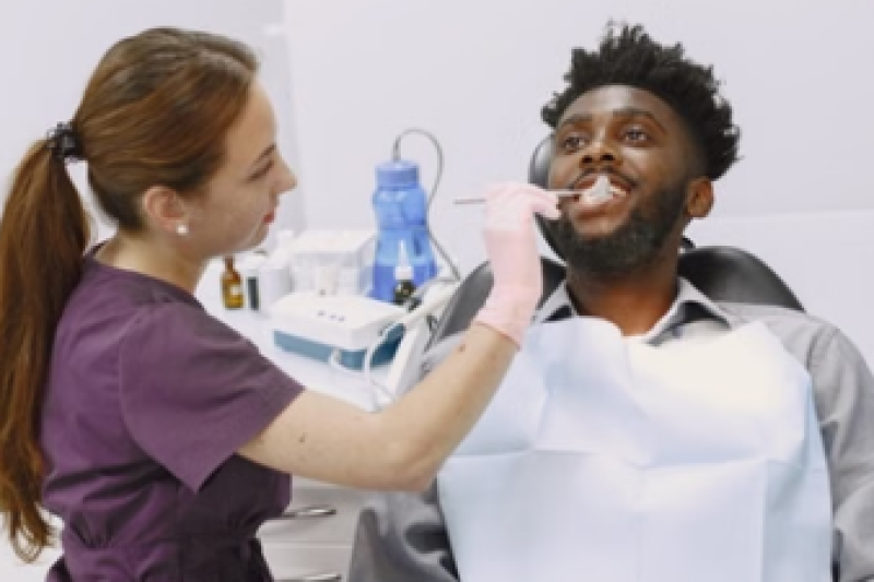Patient receiving dental treatment while seated in a dental chair as a dentist performs a procedure.