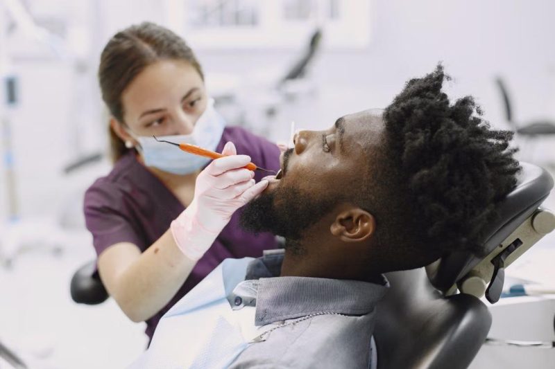 a man seated in a dentist’s chair undergoing a checkup.