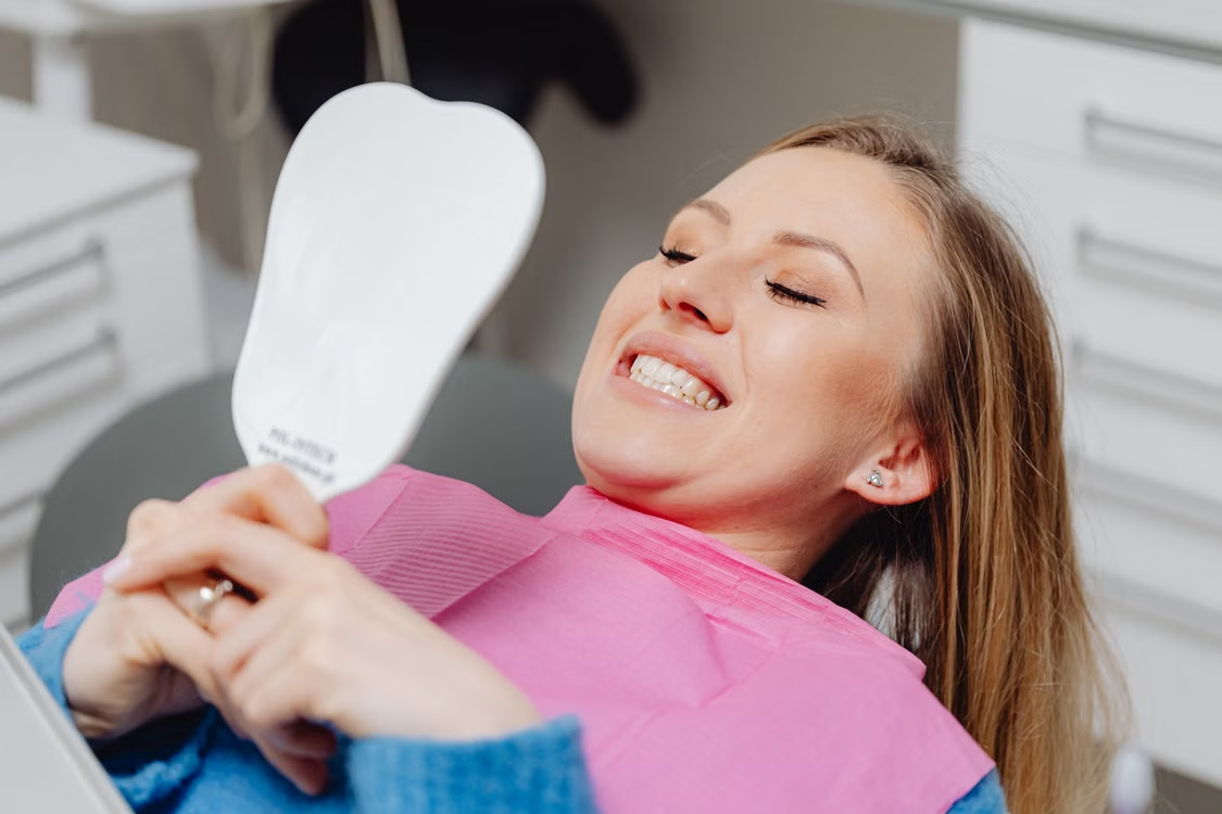 a woman checking out her teeth in a dentist chair.